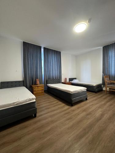 Zwei Betten in einem großen Zimmer mit Holzboden in der Unterkunft Willkommen24 in Pfullingen