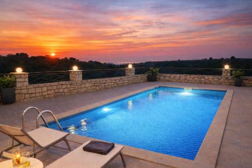 a swimming pool with a sunset in the background at Natural view villa with private pool in Skouloúfia