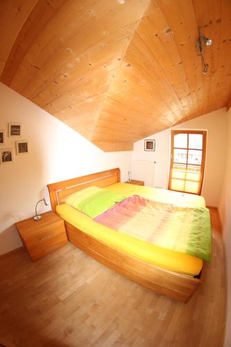 a large bed in a room with a wooden ceiling at Christina's Bergblick in Oberammergau