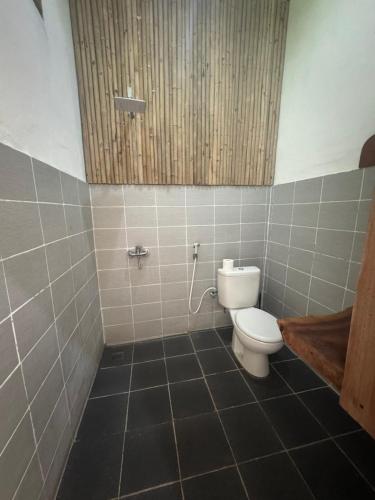 a bathroom with a toilet and a tiled floor at Blue EmOcean Dive Eco lodge in Moyo Island