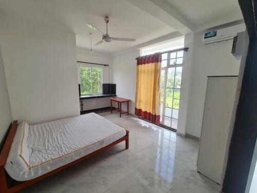 a bedroom with a bed and a kitchen with a window at A & S residences in Pannipitiya