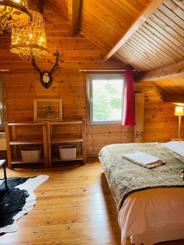 a log cabin bedroom with a bed and a window at La cabane du Cerf in Stavelot