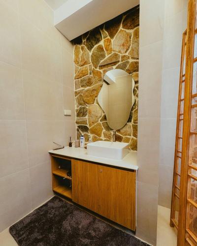 a bathroom with a sink and a stone wall at Villa Kaiyo La Union in Bacnotan