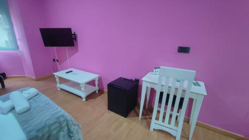 a pink room with a bed and a tv and a chair at Hotel Aro'S in Casas Ibáñez