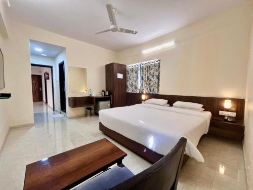 a bedroom with a bed and a desk and a table at Hotel Regency International in Jamnagar