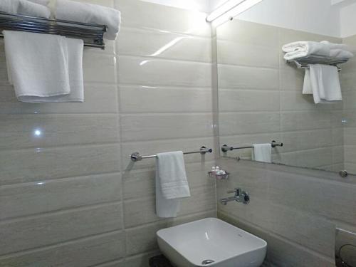 a bathroom with a toilet and a mirror and towels at Hotel Regency International in Jamnagar