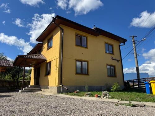 a yellow house with a roof at Casa Pietrele Doamnei in Câmpulung Moldovenesc