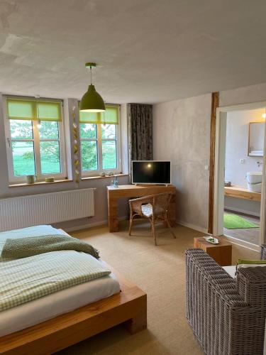 a bedroom with a bed and a desk and windows at Hotel Alte Landschule in Langballig