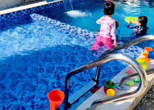 two little girls playing in a swimming pool at Omah Kebun Private Pool in Sungai Besar