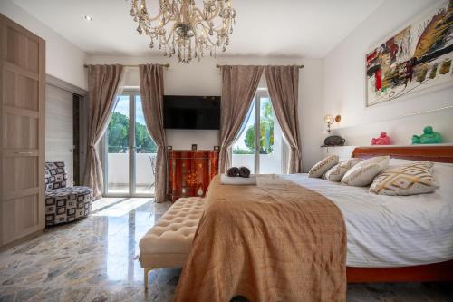 a bedroom with a large bed and a chandelier at Pink Moon Private Luxury Villa Secluded Garden 5 Bedroom 4 en suite Bathrooms with Private Pool CAT 6 WiFi Close to Beach in Fontane Bianche