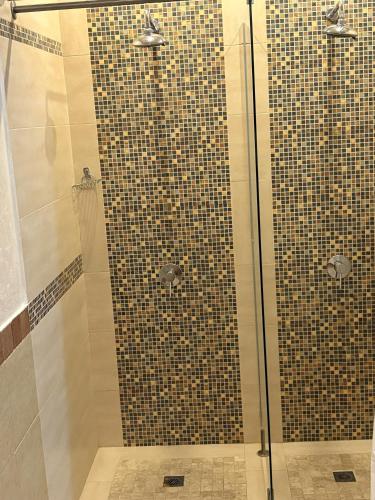 a shower with a glass door and a tile wall at Hotel Smilen in Smolyan