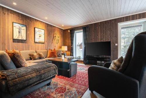 a living room with a couch and a television at Harmony in Geilo, modern and cozy cabin in Geilo