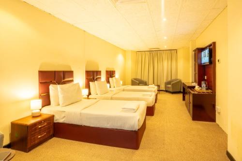 a hotel room with two beds and a television at Regal Peninsula Hotel Formerly New Peninsula Hotel Ghubaiba Bus Station Bur Dubai in Dubai