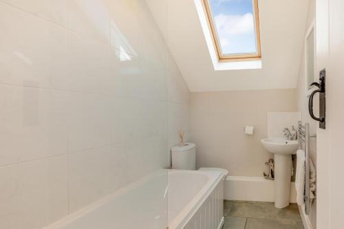 a white bathroom with a tub and a sink at 3 Bed in Beadnell oc-44965 in Beadnell
