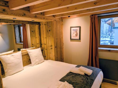 a bedroom with a bed with white sheets and a window at Les Airelles by Lodji in Saint-Marcel