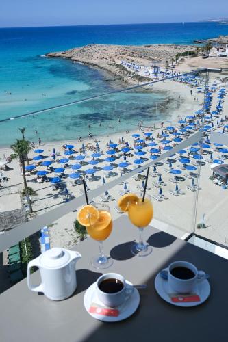 a table with drinks and a view of a beach at Chrysomare Beach Hotel & Resort in Ayia Napa