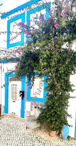 a blue and white building with a tree with flowers at Zenit Olhao baixa one bedroom house sea side view in Olhão