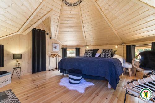 a bedroom with a bed in a room with wooden floors at Le Cocon des Cinq Sens - l'Insolite in Haute-Goulaine