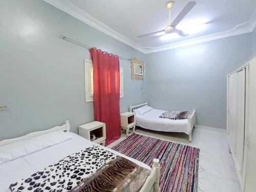 a bedroom with two beds and a red curtain at Winji Guest house in Aswan