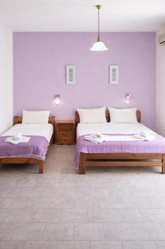 two beds in a room with purple walls at Blue Sky in Palaiochora