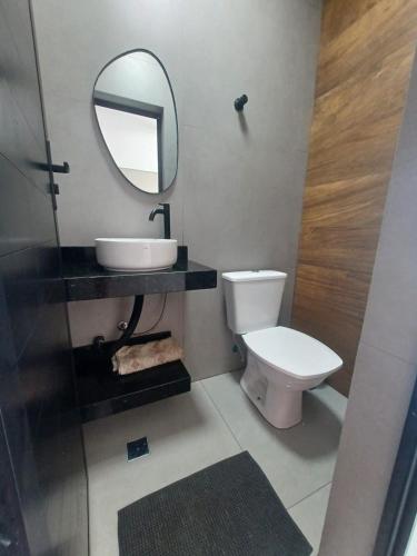 a bathroom with a sink and a toilet and a mirror at Espaço Viva Guarujá in Guarujá