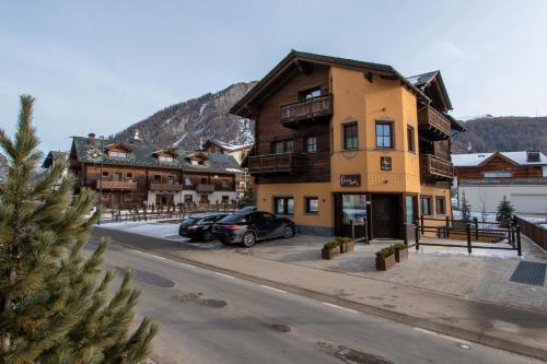 ein Gebäude, vor dem zwei Autos parken in der Unterkunft Chalet Layla by Original Galli in Livigno