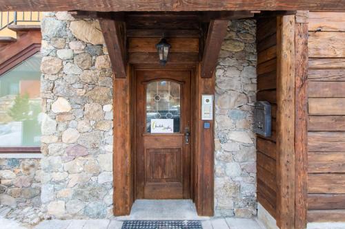 eine Holztür eines Gebäudes mit einer Steinmauer in der Unterkunft Chalet Layla by Original Galli in Livigno