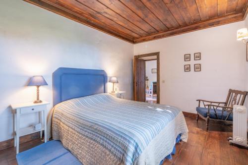 a bedroom with a blue bed and a chair at Casas da Torre Medieval - by Proguest in Refoios do Lima