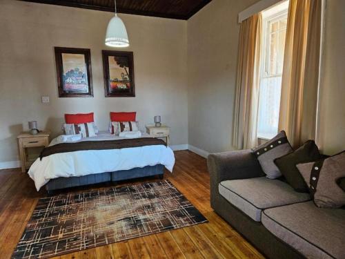 a bedroom with a bed and a couch at Arrosa Guesthouse in Vrede