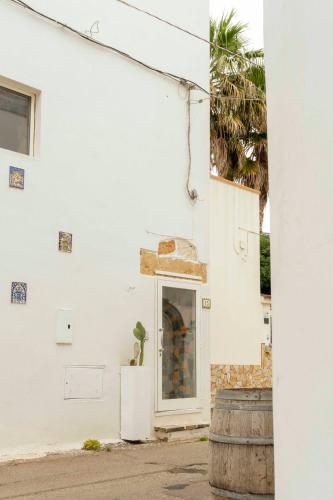 a white building with a door and a plant on a barrel at Zen Palazzo Storico in Alliste