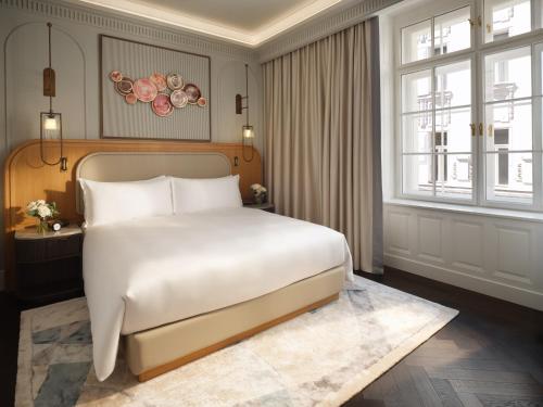 a bedroom with a white bed and a large window at Mandarin Oriental, Vienna in Vienna