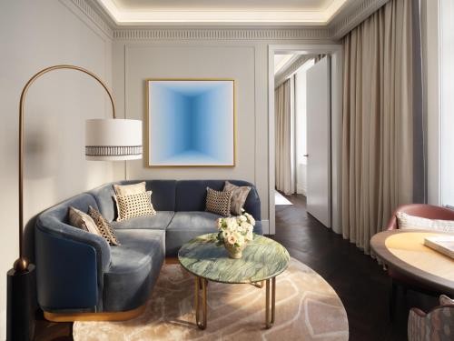 a living room with a blue couch and a table at Mandarin Oriental, Vienna in Vienna