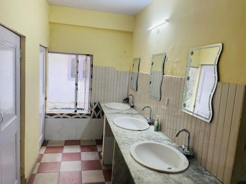 a bathroom with three sinks and mirrors on the wall at Abuzz Oxfordcaps Simla in Shimla