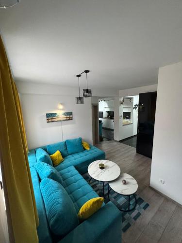 un salon avec un canapé bleu et deux tables dans l'établissement Apartman 