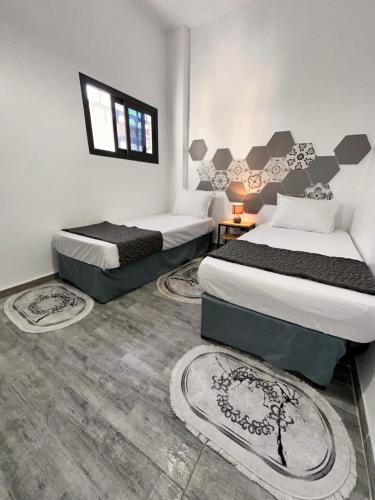 two beds in a room with rugs on the floor at Dar el bahdja in Sidi MʼHamed