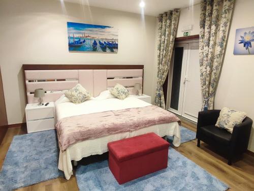 a bedroom with a large bed and a red stool at NetosResidence in Freixo de Baixo