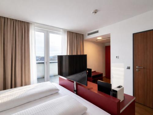 a bedroom with a bed with a flat screen tv at DORMERO DeHo Linz in Linz