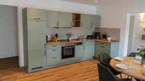 a kitchen with white cabinets and a table and a dining room at Pension Spreewald Lächeln - Apartment Kahnfahrt durch den Spreewald in Treppendorf