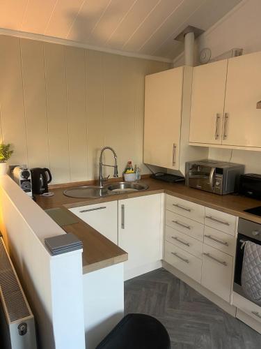 a kitchen with white cabinets and a sink at The Eden, Cosy 1 bed lodge with riverside views in Crieff