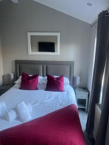 a bedroom with a large bed with red pillows at The Eden, Cosy 1 bed lodge with riverside views in Crieff