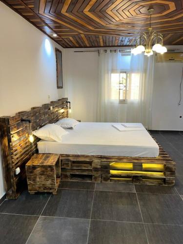 a bedroom with a large bed with a wooden headboard at Maison meublée Odza Yaoundé in Yaoundé