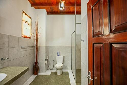 a bathroom with a toilet and a glass shower at Samadhi Yoga Resort in Bentota