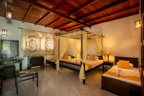 a bedroom with two beds and a canopy bed at Samadhi Yoga Resort in Bentota
