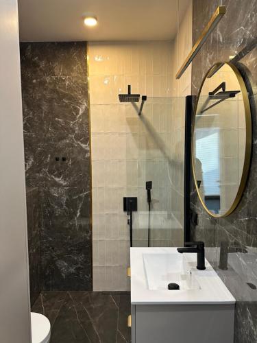 a bathroom with a sink and a mirror at Brzostek Apartamenty in Marki