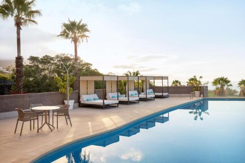 a swimming pool with a table and chairs next to a building at AluaSoul Orotava Valley - Adults Only in Puerto de la Cruz