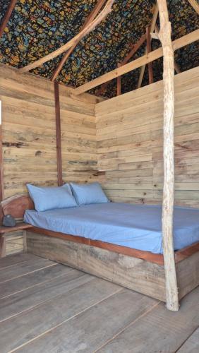 a bed in a wooden cabin with a roof at Terema Lodge in Kanuma