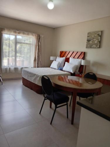 a bedroom with a bed and a table and a desk at Hlalanathi Lodge - 9 Shepstone Road, Harding in Harding
