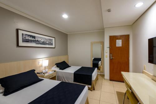 ein Hotelzimmer mit zwei Betten und einem Badezimmer in der Unterkunft Hotel Maione in Goiânia