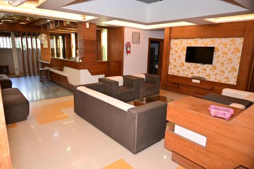 a living room with a couch and a flat screen tv at Sri Shivam Hotel in Gondia