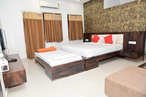 a bedroom with two beds with red pillows at Sri Shivam Hotel in Gondia
